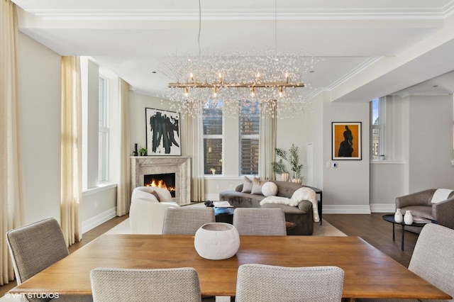 dining area featuring a premium fireplace, crown molding, a chandelier, and hardwood / wood-style flooring