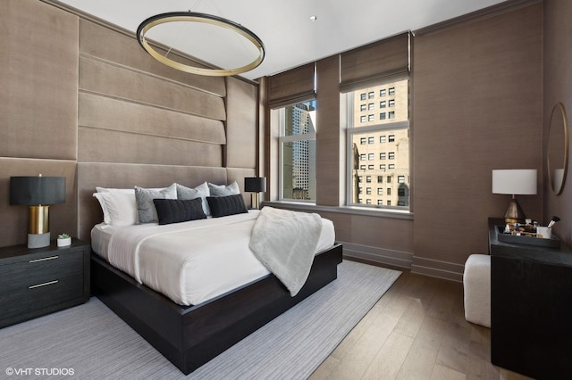 bedroom with light wood-type flooring and wood walls