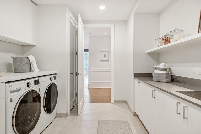 washroom featuring cabinets, separate washer and dryer, light tile patterned floors, and sink