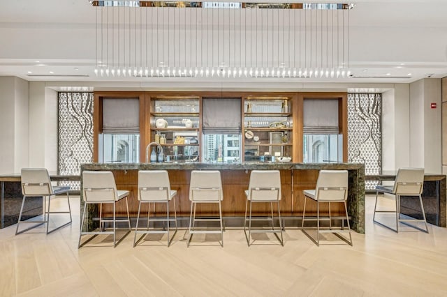 bar with dark stone countertops and hanging light fixtures