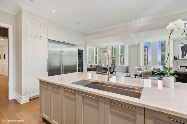 kitchen featuring sink, light hardwood / wood-style flooring, built in refrigerator, and light stone countertops