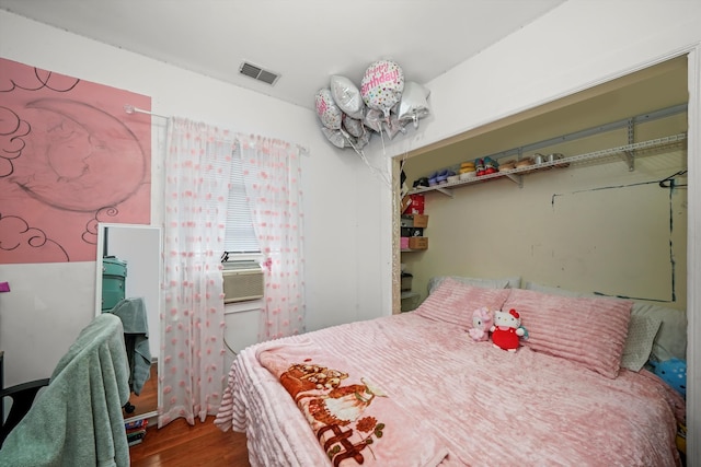 bedroom featuring hardwood / wood-style flooring, cooling unit, and a closet