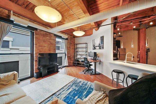 living room featuring beamed ceiling, hardwood / wood-style flooring, wooden ceiling, and brick wall