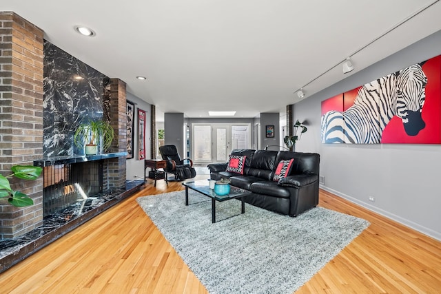 living room with a brick fireplace, hardwood / wood-style flooring, and track lighting