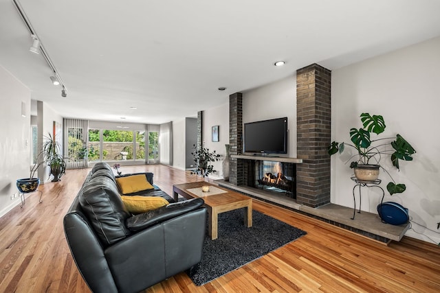 living room with light hardwood / wood-style floors, track lighting, and a fireplace