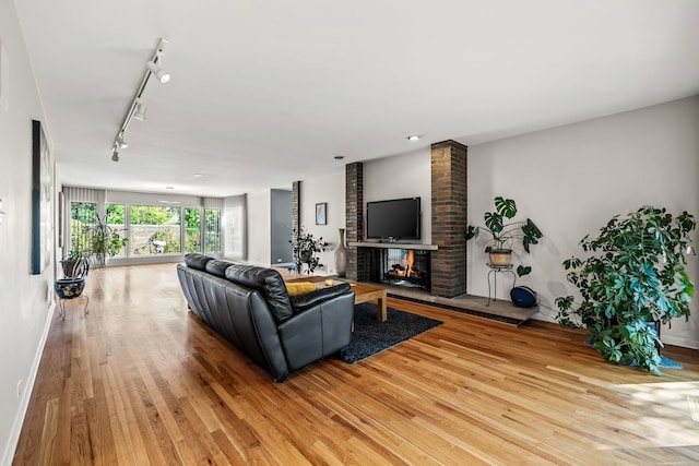 living room with light wood-type flooring, track lighting, and a fireplace