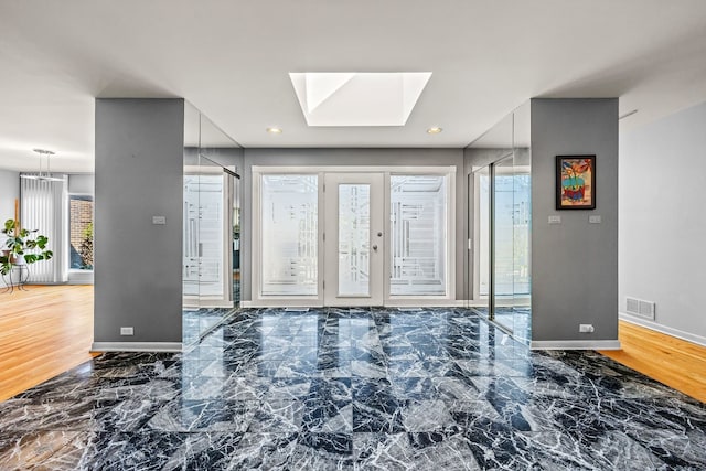 interior space with a skylight and dark hardwood / wood-style flooring