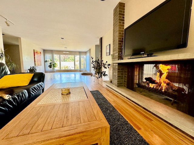 living room featuring a brick fireplace and wood-type flooring