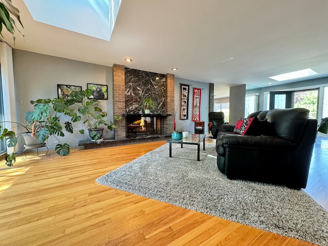 living room featuring a fireplace, a skylight, and hardwood / wood-style flooring