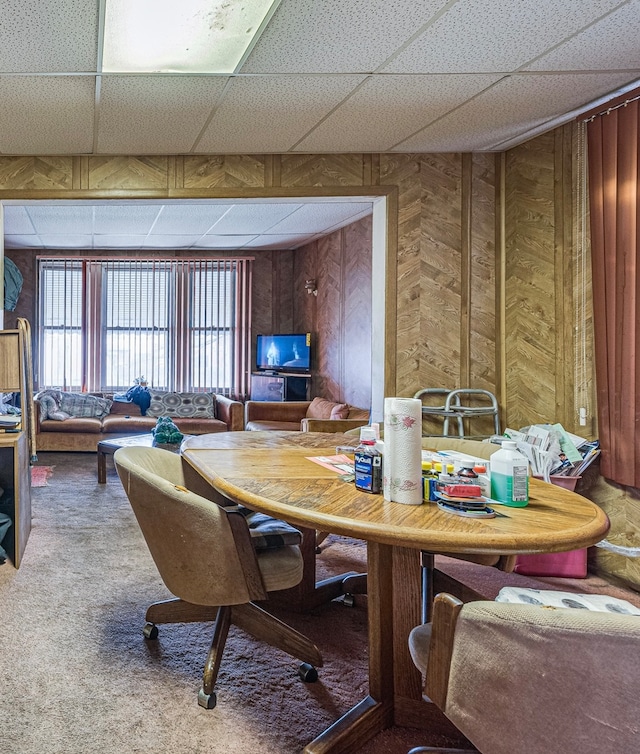 dining area featuring wood walls, a paneled ceiling, and carpet