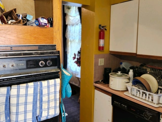 kitchen with black dishwasher, decorative backsplash, and white cabinetry