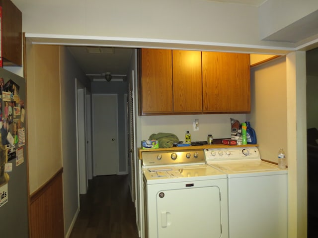 washroom with washing machine and clothes dryer, dark hardwood / wood-style floors, and cabinets