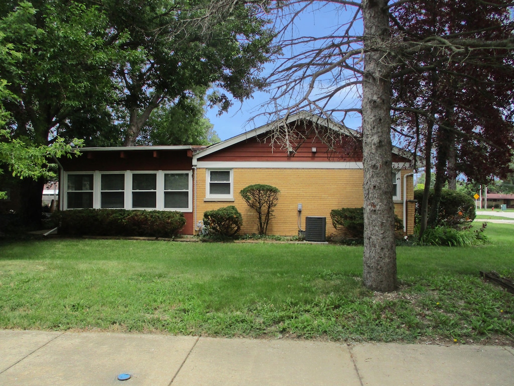 ranch-style home featuring a front lawn and central air condition unit