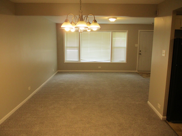 carpeted spare room featuring an inviting chandelier