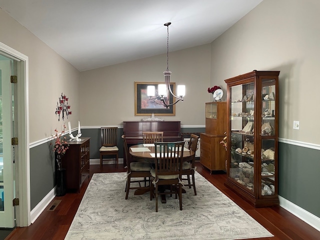 dining space with lofted ceiling, a chandelier, and dark hardwood / wood-style floors