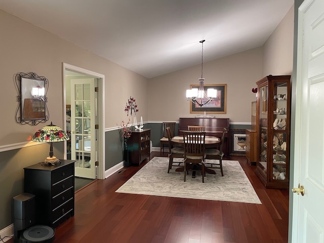 dining area featuring dark wood-type flooring, a chandelier, and vaulted ceiling