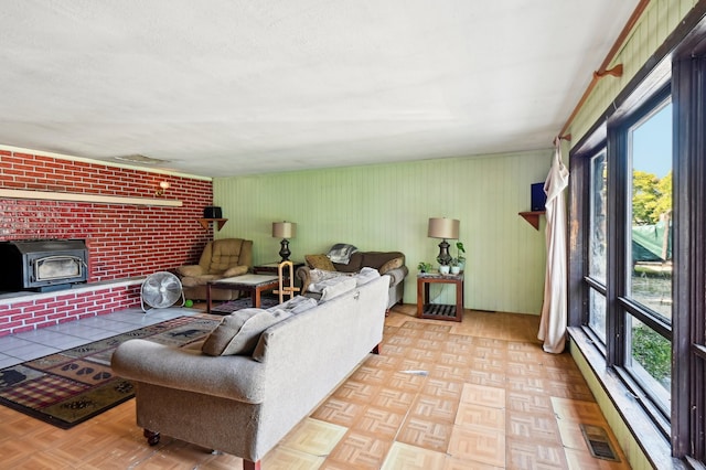 living room with brick wall, a wood stove, and light parquet flooring