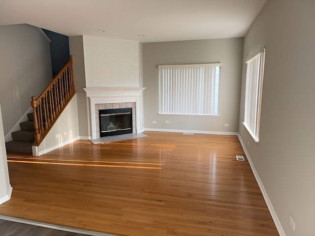 unfurnished living room with a tiled fireplace and hardwood / wood-style flooring