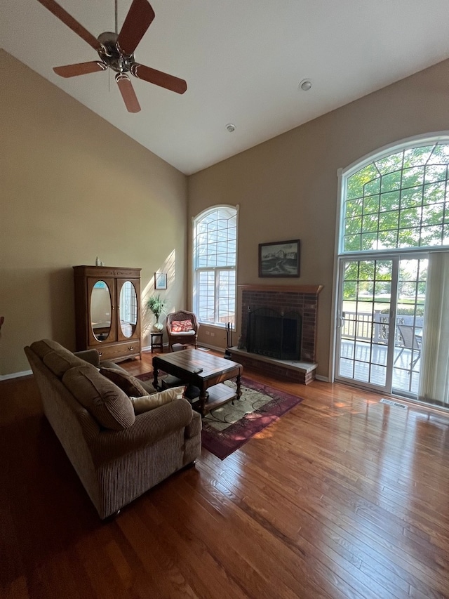 living room with ceiling fan, high vaulted ceiling, hardwood / wood-style flooring, and a fireplace