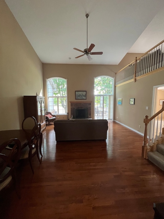 living room with dark wood-type flooring, ceiling fan, and a wealth of natural light