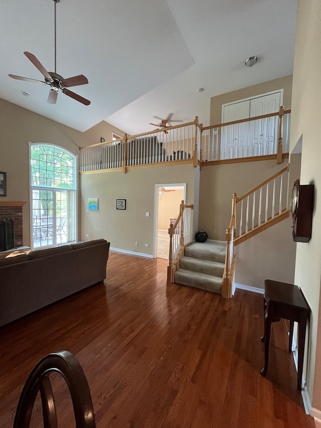 living room featuring a fireplace, dark wood-type flooring, and ceiling fan