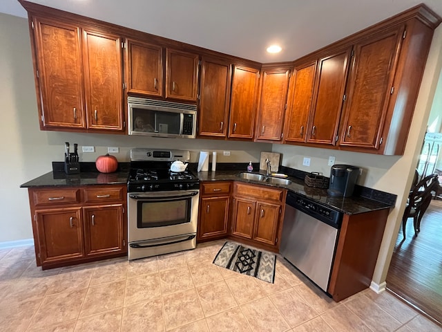 kitchen featuring sink, appliances with stainless steel finishes, dark stone counters, and light hardwood / wood-style floors