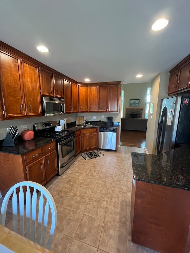 kitchen featuring dark stone countertops, light tile patterned floors, stainless steel appliances, and sink