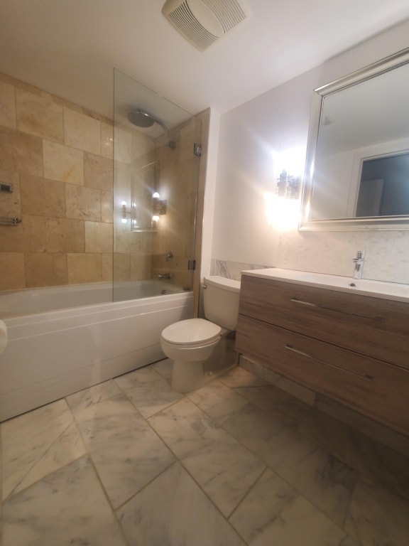 full bathroom with tiled shower / bath combo, vanity, and toilet