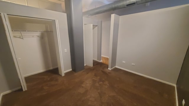 unfurnished bedroom featuring dark carpet and a closet