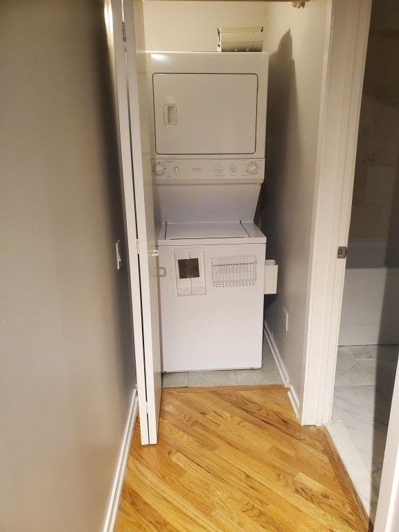 laundry room featuring stacked washer / dryer and light hardwood / wood-style floors