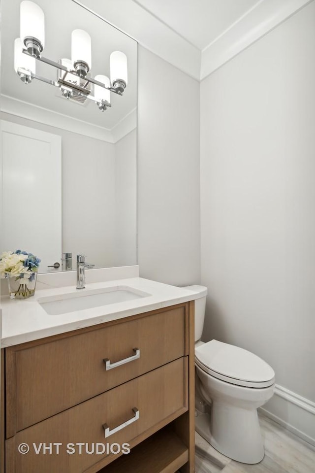 bathroom featuring vanity, crown molding, a chandelier, and toilet