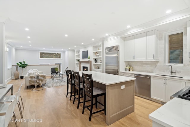 kitchen featuring a kitchen island, sink, white cabinets, a kitchen breakfast bar, and stainless steel appliances