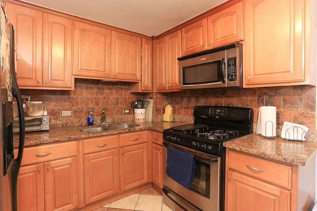 kitchen featuring stainless steel appliances, sink, decorative backsplash, stone countertops, and light tile patterned flooring