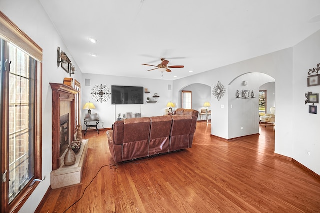 living room with hardwood / wood-style flooring, a tile fireplace, and ceiling fan