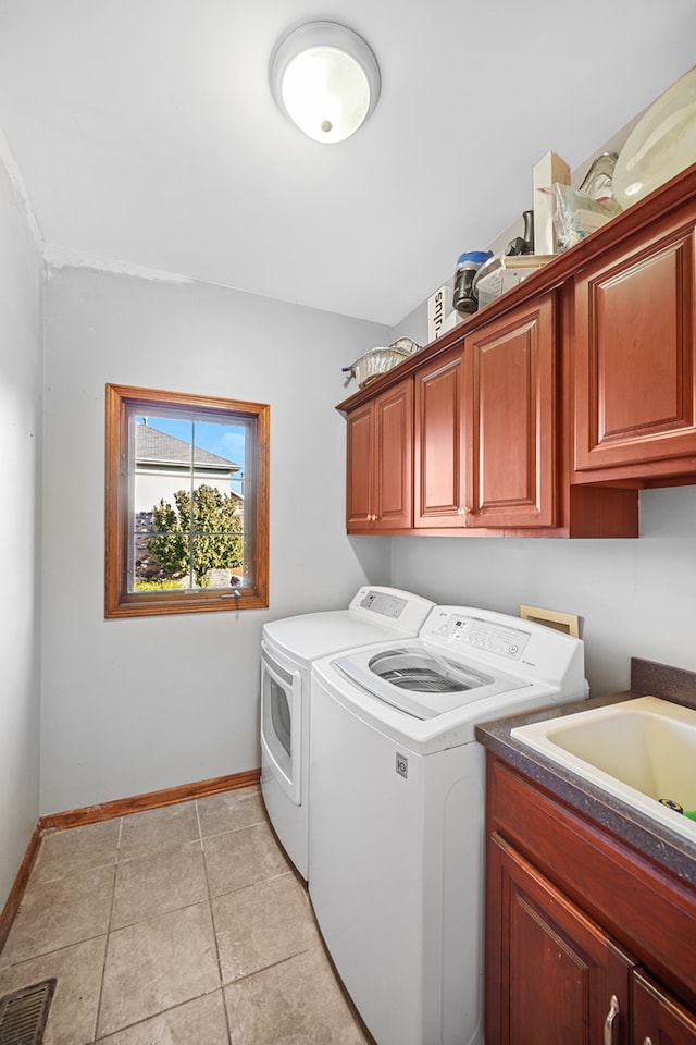 laundry room featuring light tile patterned floors, separate washer and dryer, and cabinets