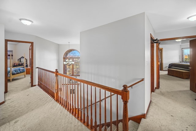 hall with a notable chandelier and light carpet