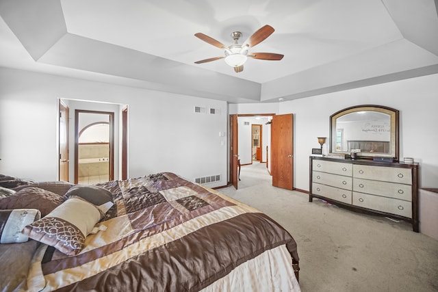 carpeted bedroom with connected bathroom, a tray ceiling, and ceiling fan