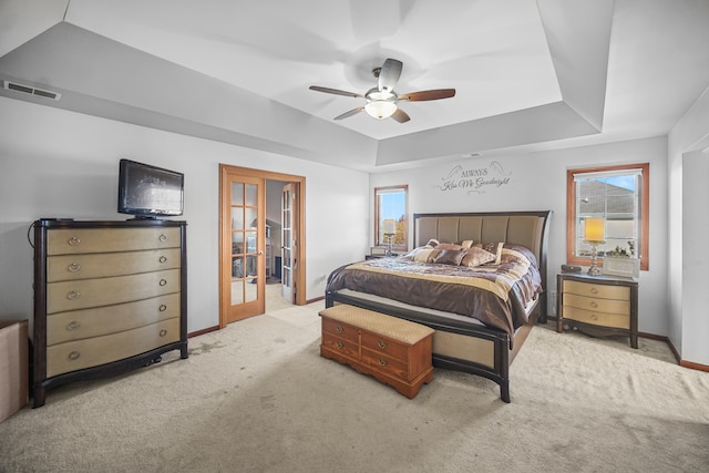 bedroom featuring ceiling fan, light carpet, and a raised ceiling