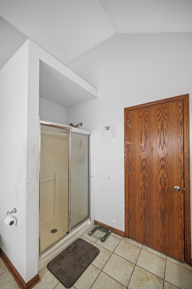 bathroom with lofted ceiling, a shower with shower door, and tile patterned flooring