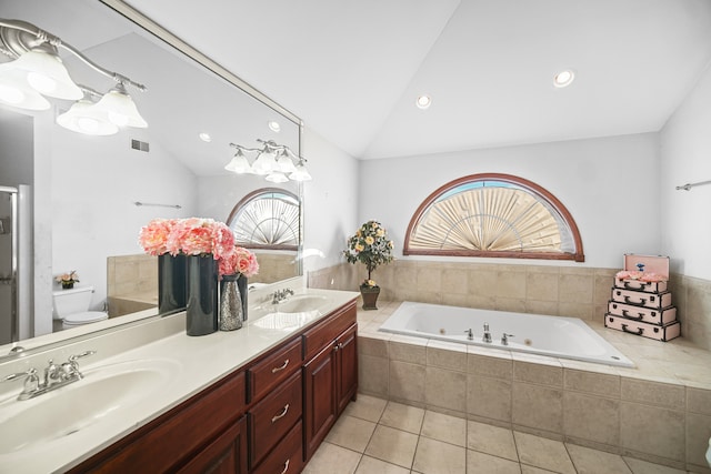 bathroom with lofted ceiling, toilet, a relaxing tiled tub, vanity, and tile patterned floors