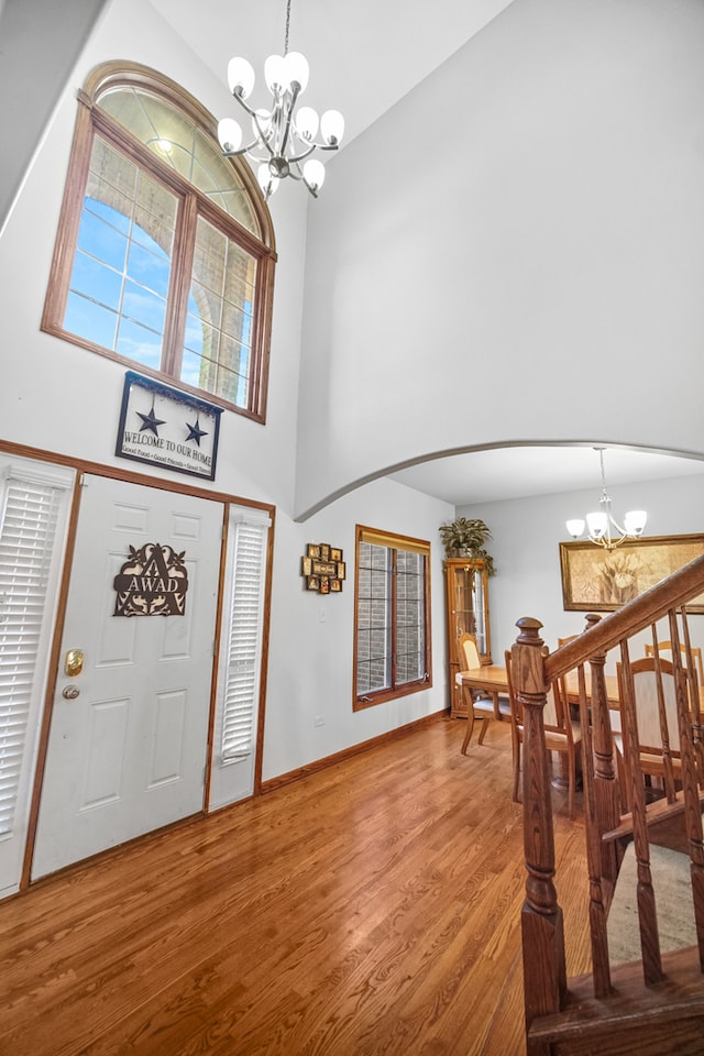 foyer featuring a chandelier, wood-type flooring, and a high ceiling