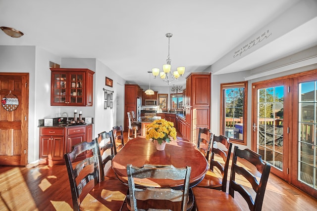 dining area with sink, light hardwood / wood-style flooring, and an inviting chandelier