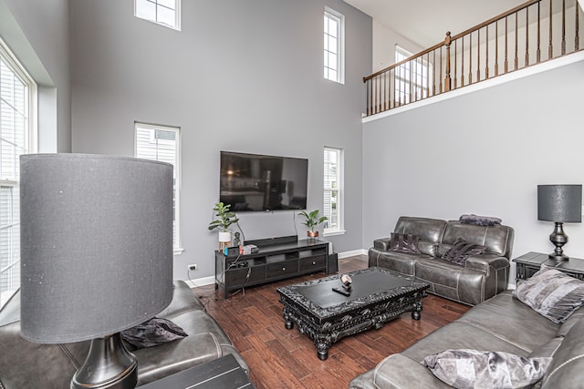 living room featuring a towering ceiling, dark hardwood / wood-style floors, and a healthy amount of sunlight