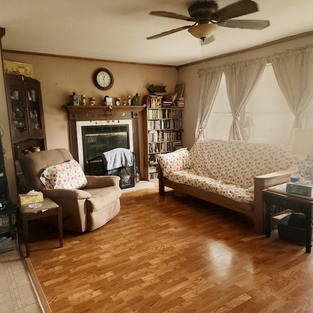 living room with ceiling fan, a fireplace, wood-type flooring, and ornamental molding