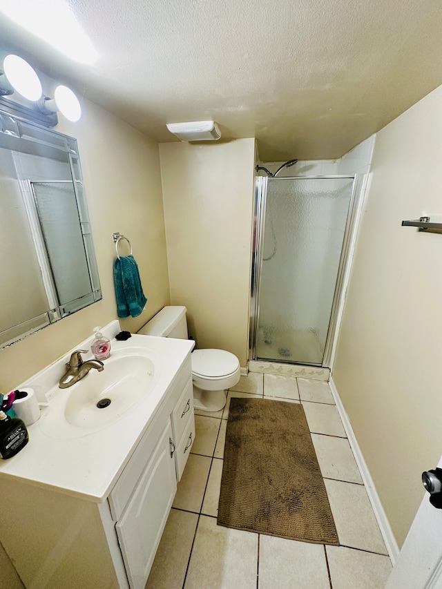 bathroom with a textured ceiling, toilet, walk in shower, vanity, and tile patterned flooring