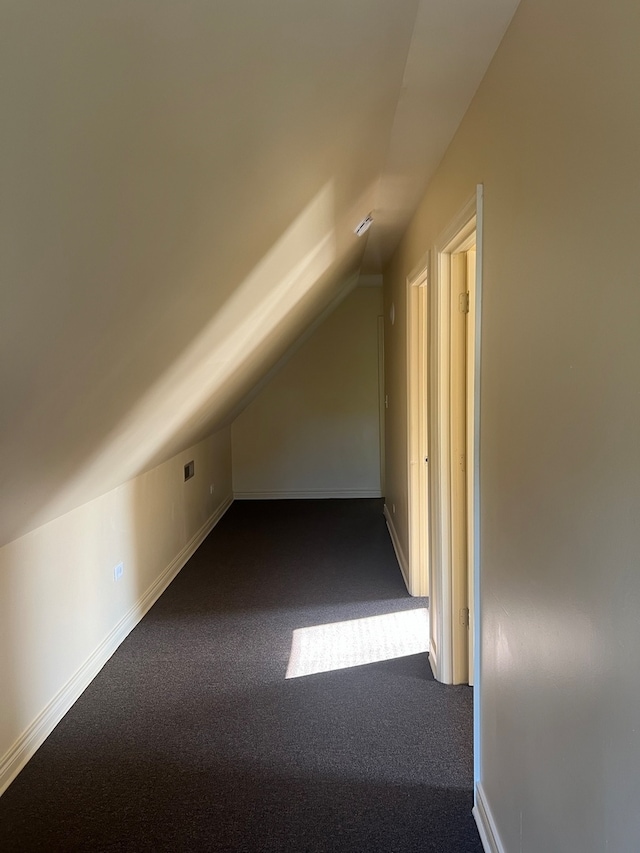 bonus room featuring lofted ceiling and dark colored carpet