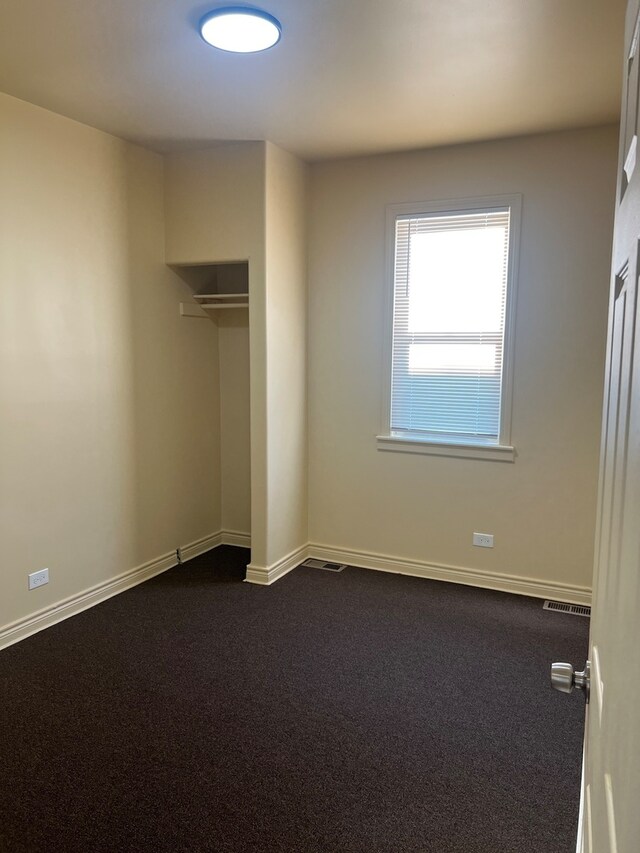 unfurnished bedroom with a closet and dark colored carpet