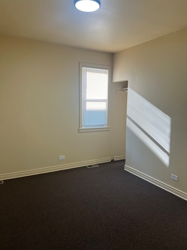 spare room with dark colored carpet