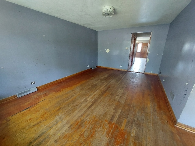 spare room with wood-type flooring, baseboards, and visible vents