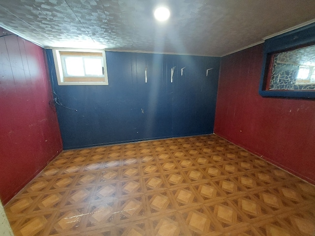 basement featuring wood walls and parquet flooring